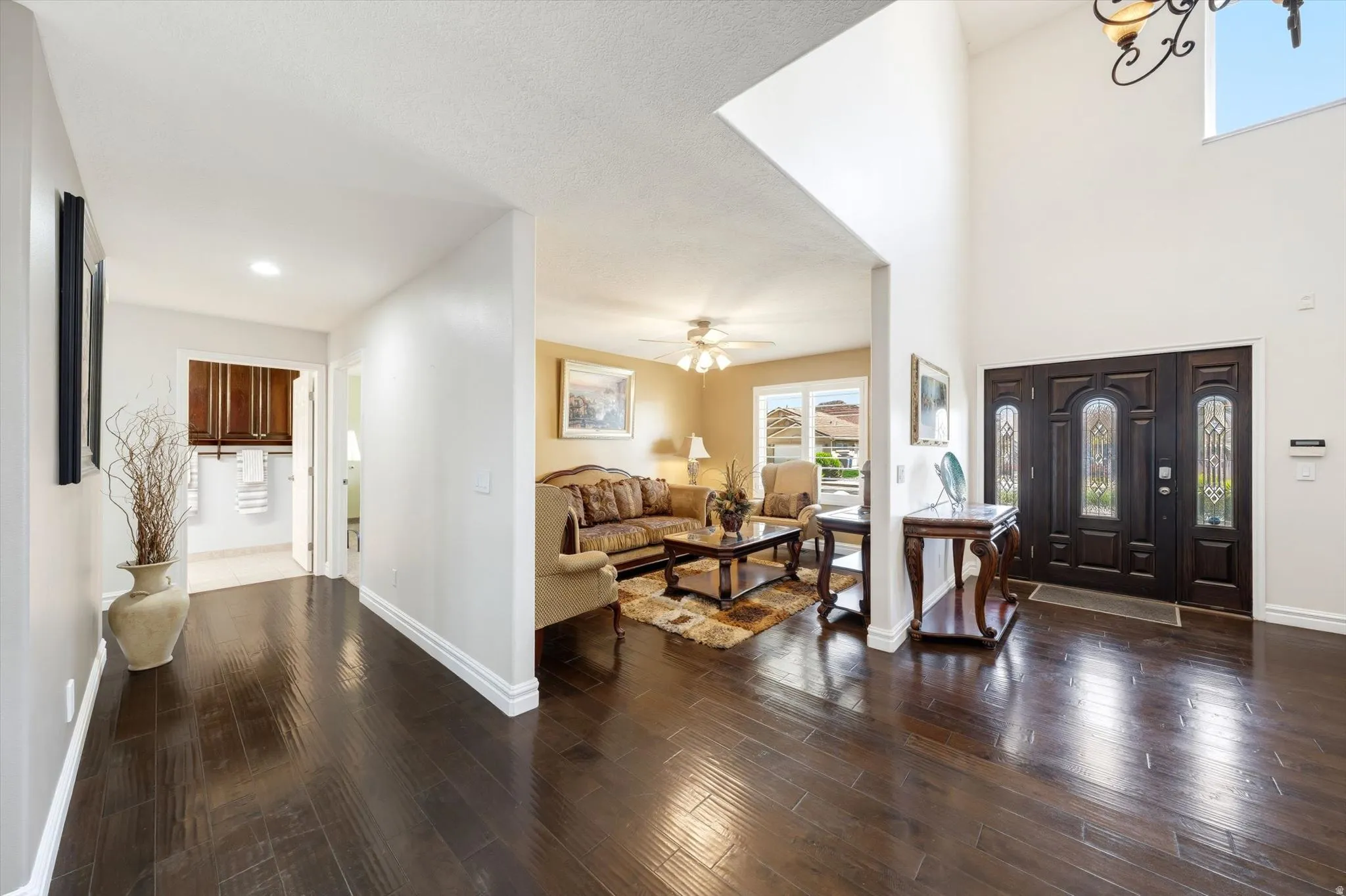 Grand entryway featuring a double door with decorative glass inserts, soaring ceilings, and a large chandelier