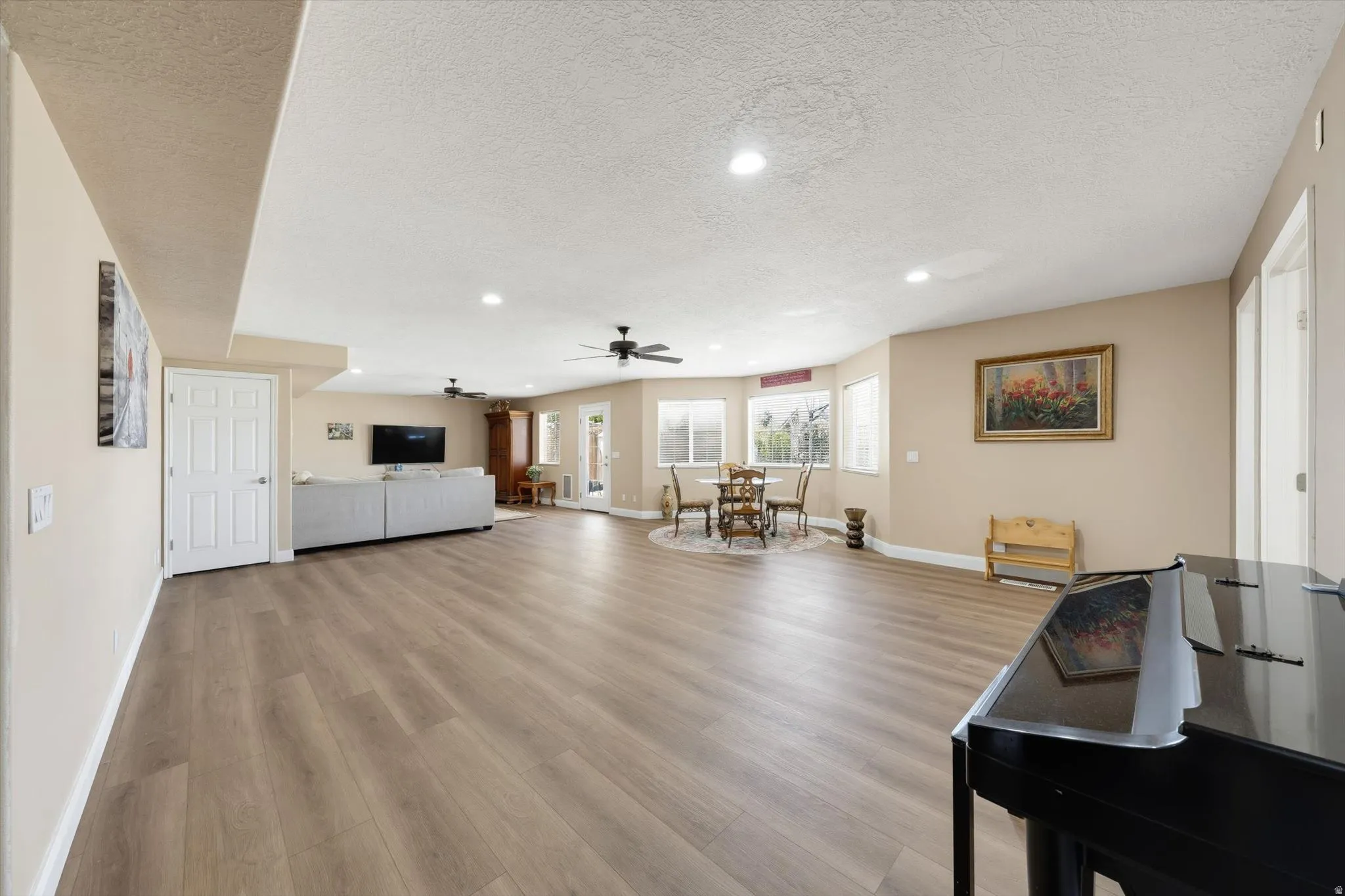 Expansive open-concept living area featuring wood-finish flooring, recessed lighting, and ceiling fans