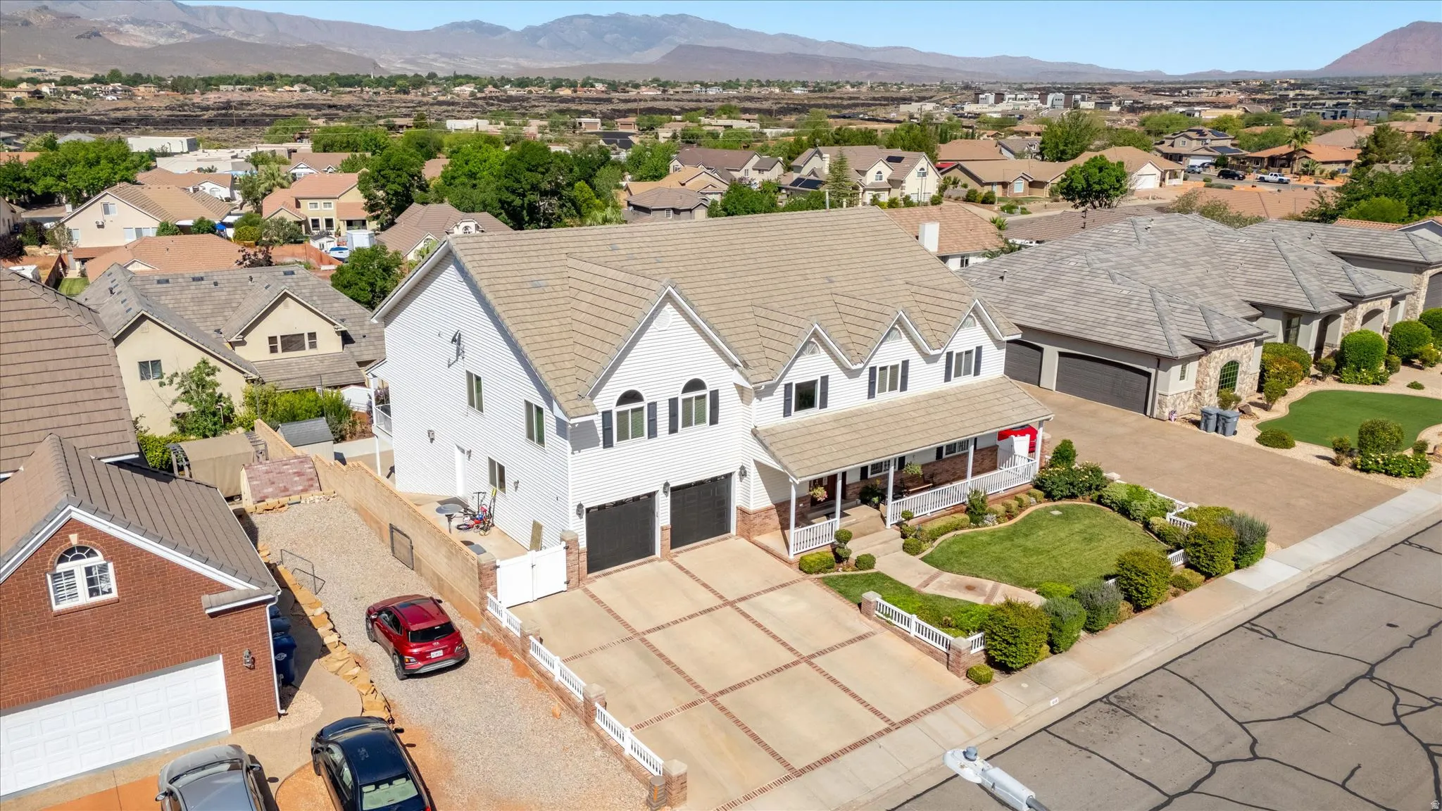 Two-story residence featuring a covered front porch, white exterior siding, arched windows, and a two-car garage