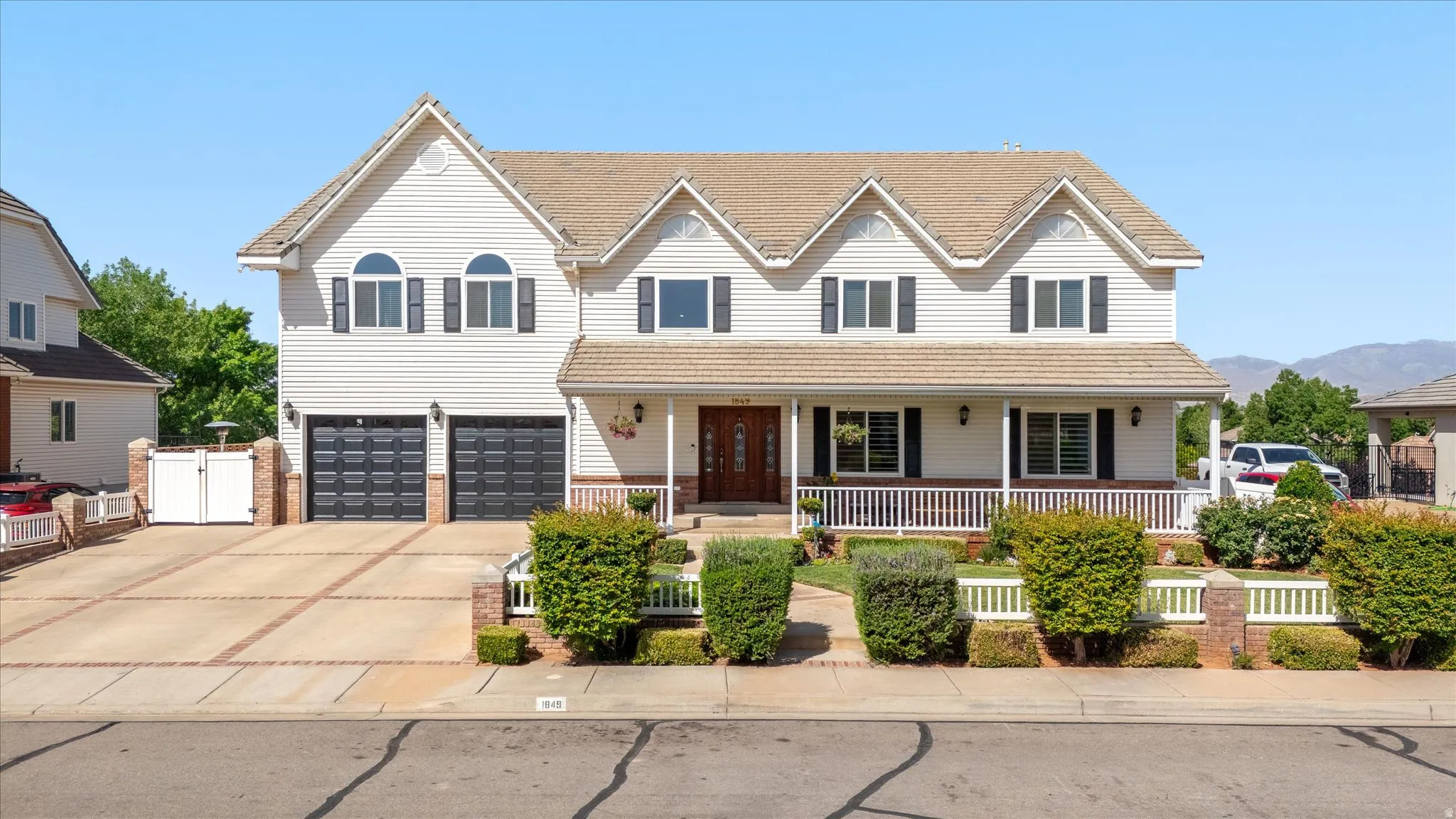 Two-story residence featuring light-colored siding, a covered front porch, and a two-car garage with dark paneled doors