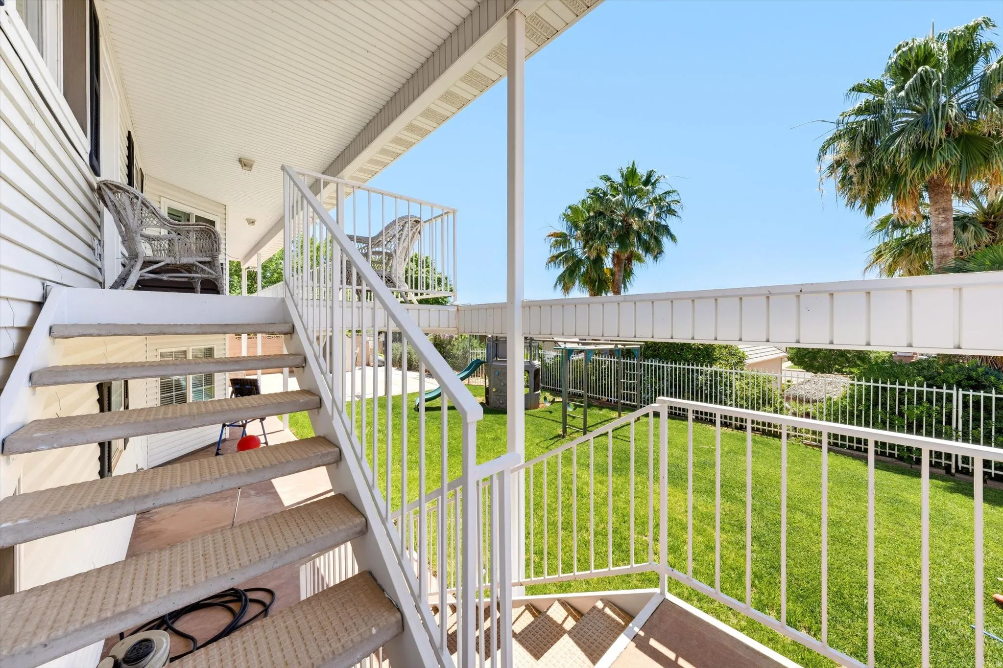 Multi-level outdoor living space featuring a white metal staircase and railing system