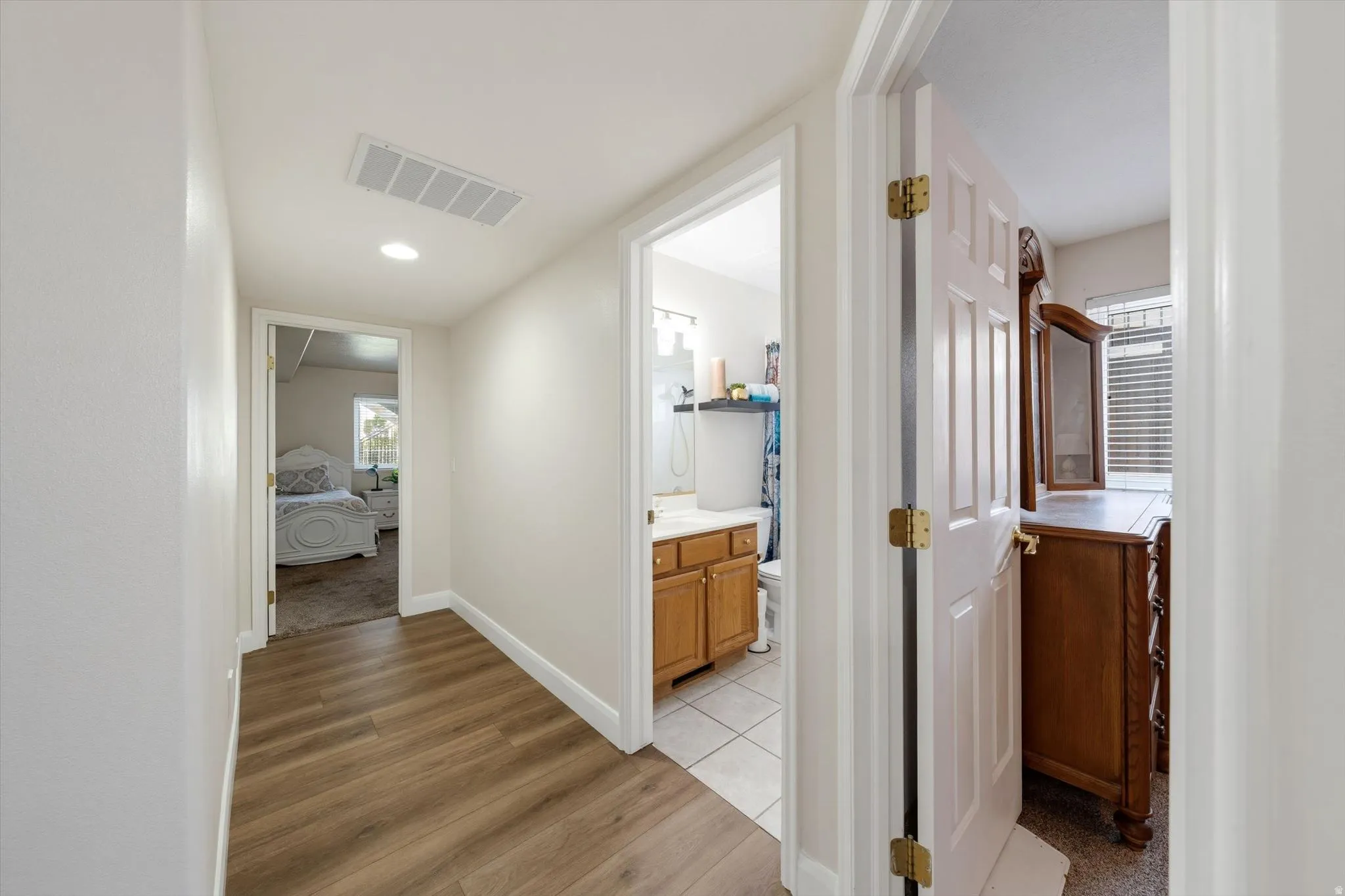Hallway featuring wood-finish flooring, recessed lighting, and an overhead air vent