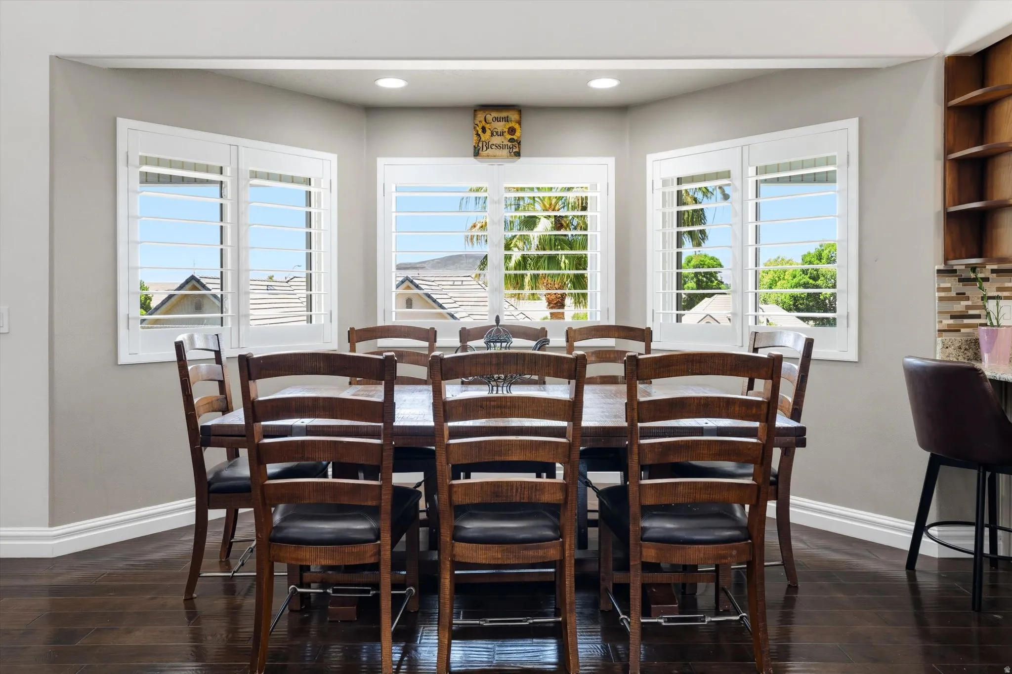 Dining area featuring bay windows with white plantation shutters, recessed lighting, and dark wood-finish flooring