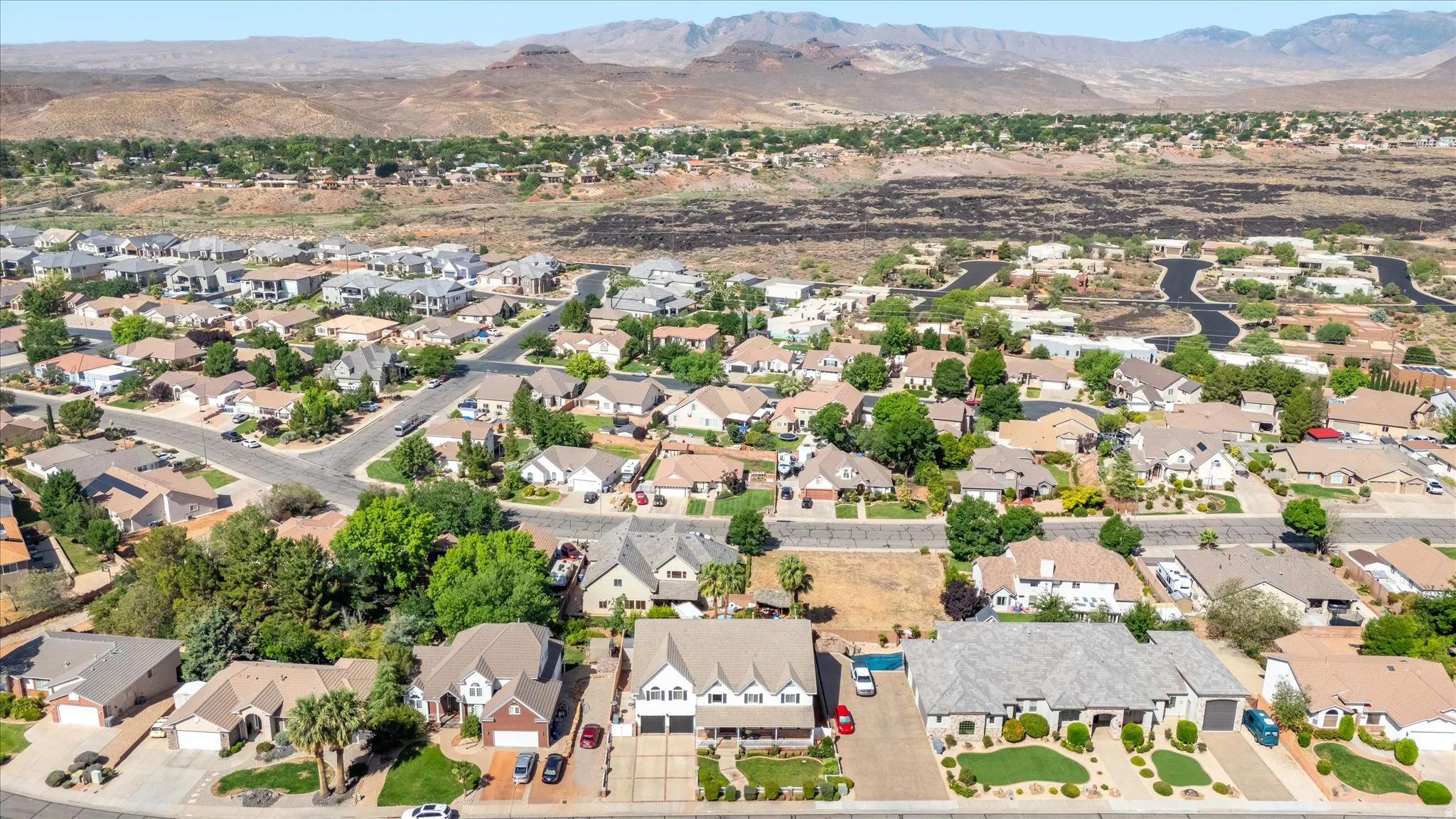 Residential neighborhood featuring a variety of single-story and multi-story homes, mature landscaping, paved streets, and mountain terrain in the background