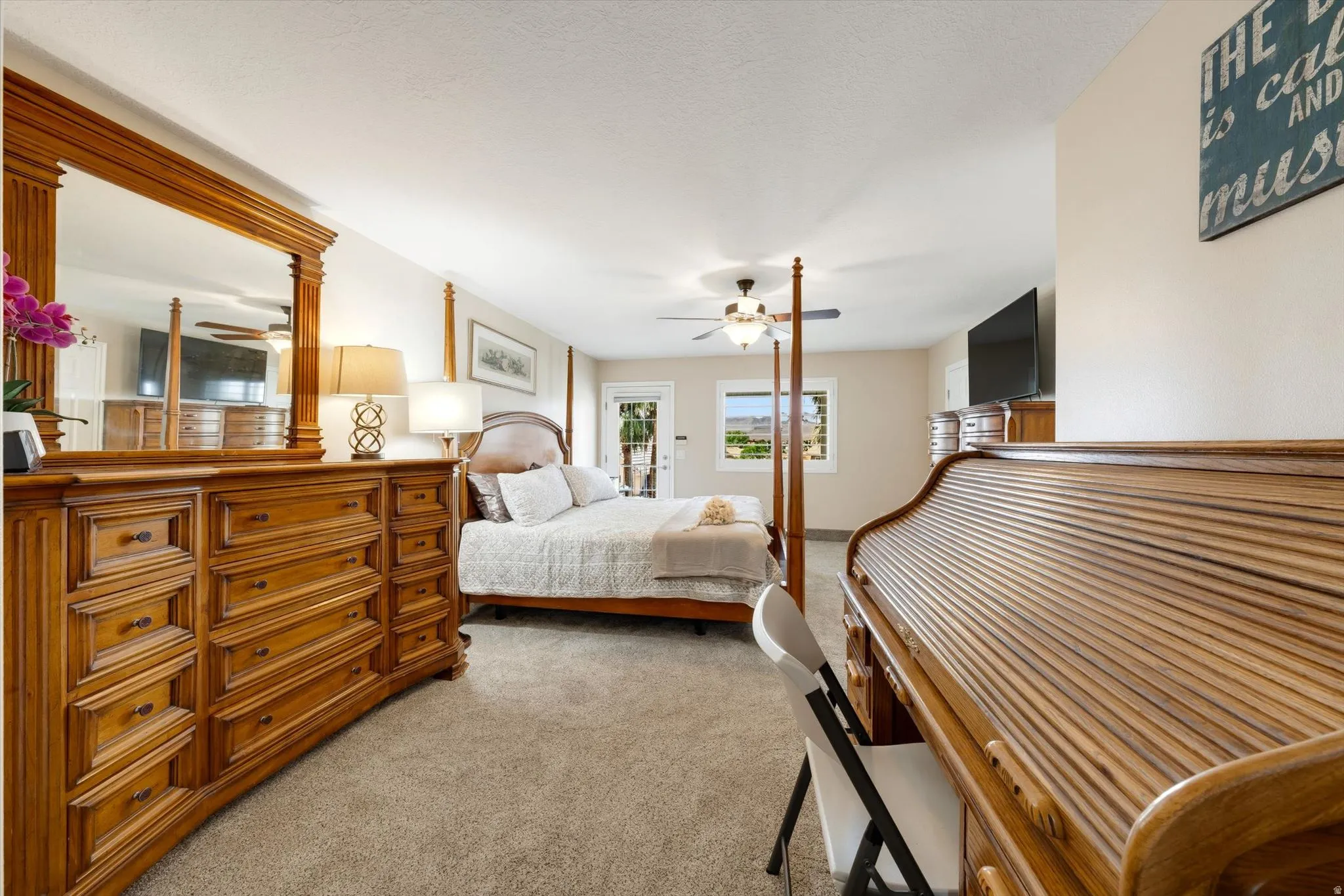 Neutral tone wall paint, carpeted flooring, ceiling fan light fixture, and exterior-facing door