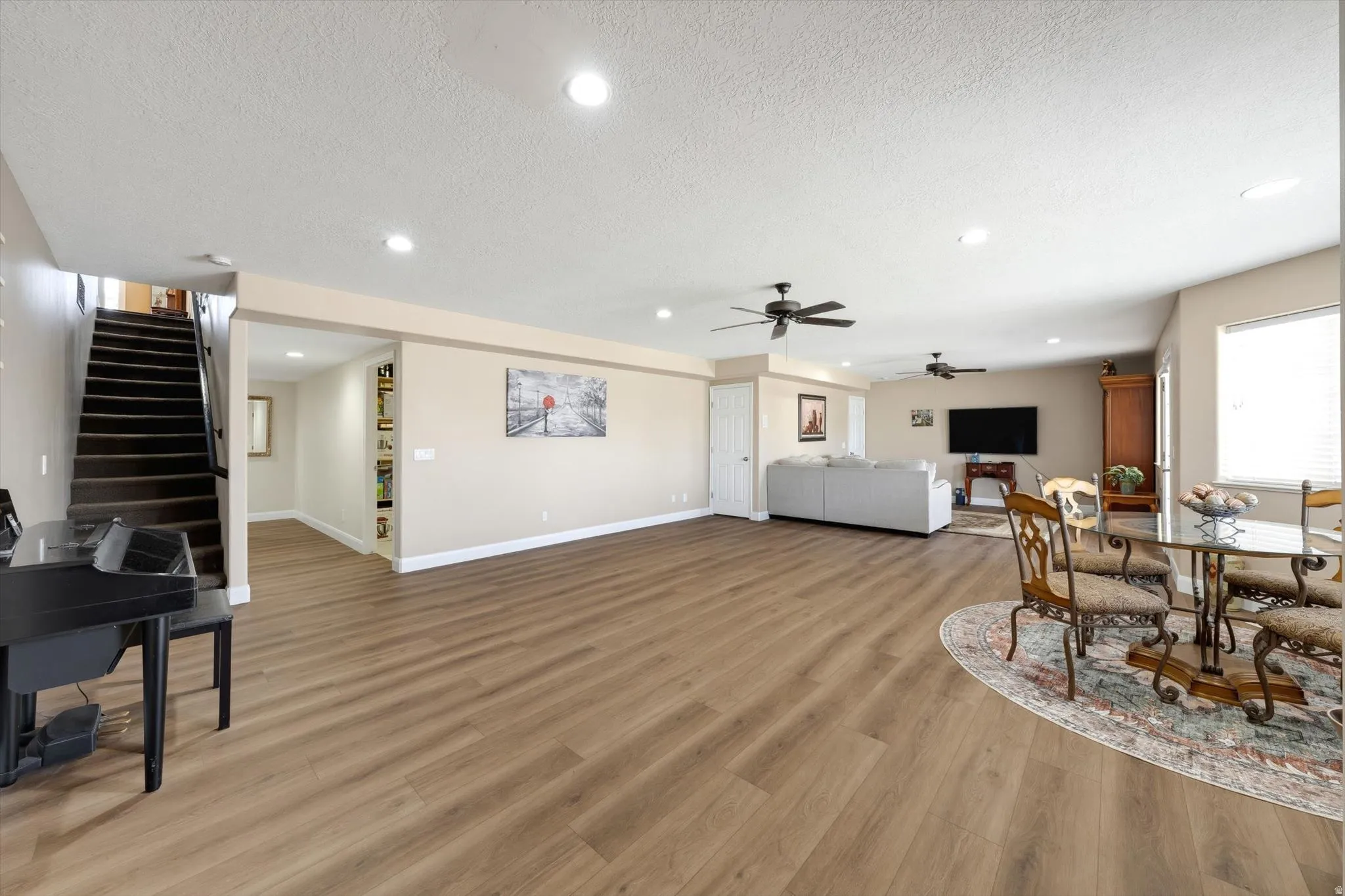 Expansive room featuring wood-finish flooring, recessed lighting, and a ceiling fan