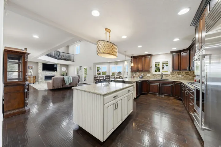 Open-concept living area featuring a kitchen island with white cabinetry, dark wood-finish flooring, and recessed lighting