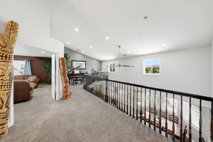 Spacious loft area featuring vaulted ceilings, recessed lighting, and soft carpet flooring