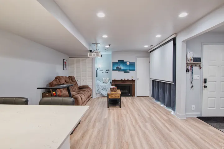 Open-concept area featuring wood-finish flooring, recessed lighting, and a built-in projector screen