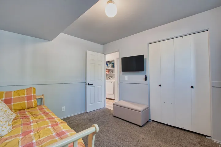 Carpeted room with a two-tone painted wall featuring a white four-panel closet with black circular knobs