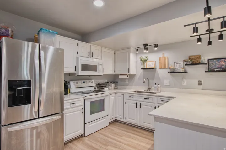 Bright kitchen featuring light wood-finish flooring and white cabinetry with dark hardware