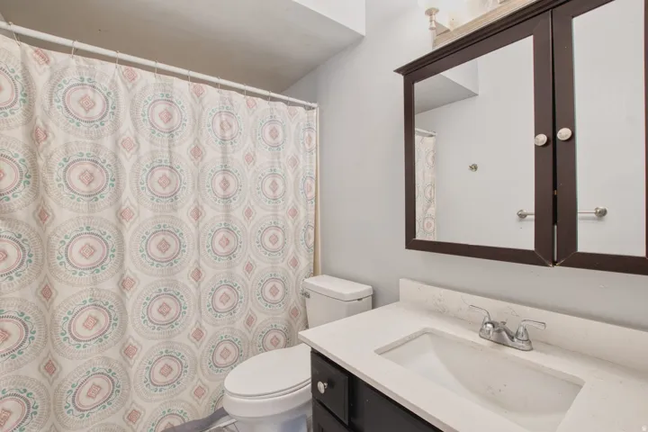 Bathroom featuring a white vanity with an integrated sink, chrome faucet, dark wood-finish cabinetry, and a dark wood-finish medicine cabinet with mirrored doors