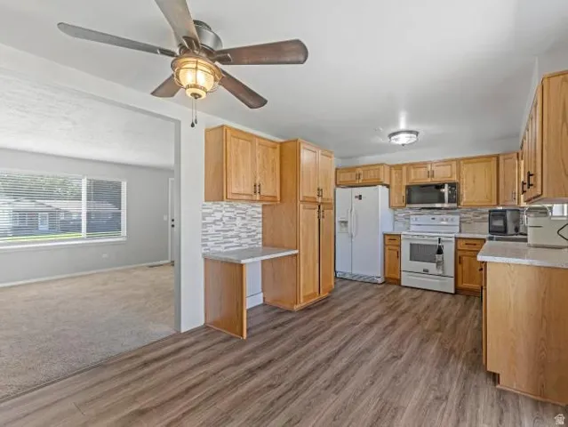 Kitchen featuring wood-finish flooring, wood cabinetry, stone-finish countertops, and a tile backsplash