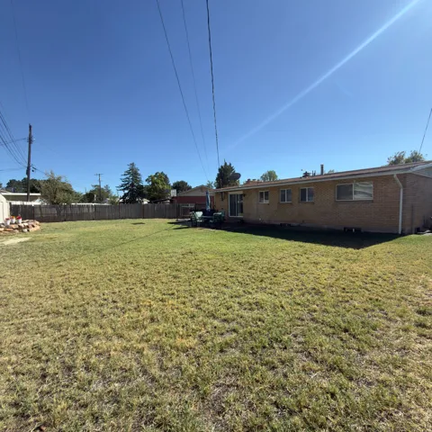 Expansive backyard featuring a full wood privacy fence, a brick exterior, and a sliding glass patio door
