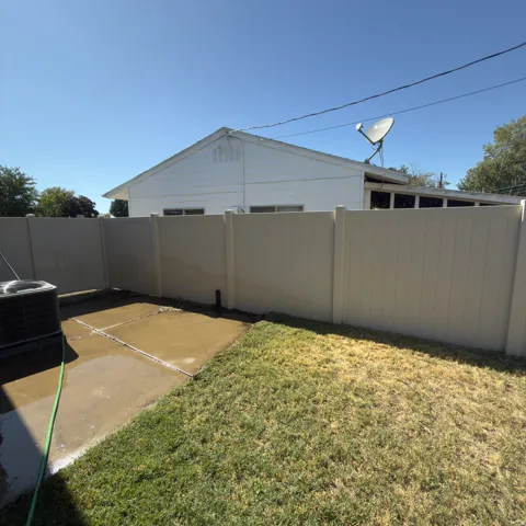 Private yard featuring a vinyl fence, concrete patio, and a grass area