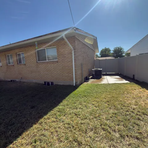 Brick exterior with multiple windows, concrete patio, and a privacy fence