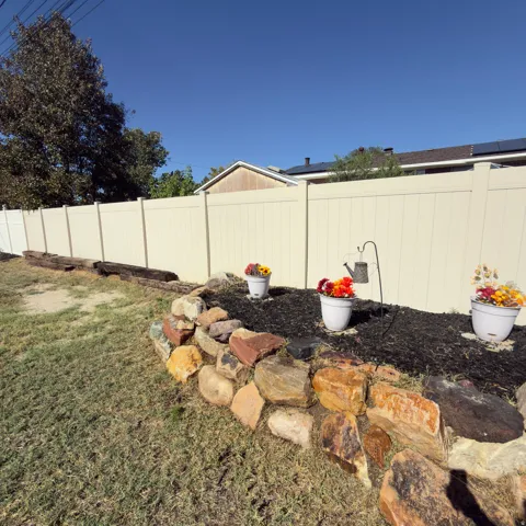 Expansive lawn area featuring a decorative stone retaining wall and a privacy fence