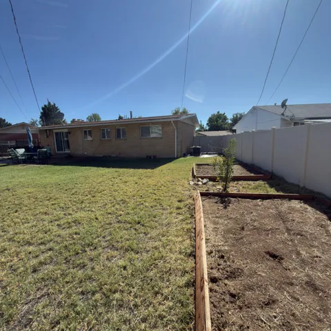 Expansive grassy yard with raised garden beds and a privacy fence