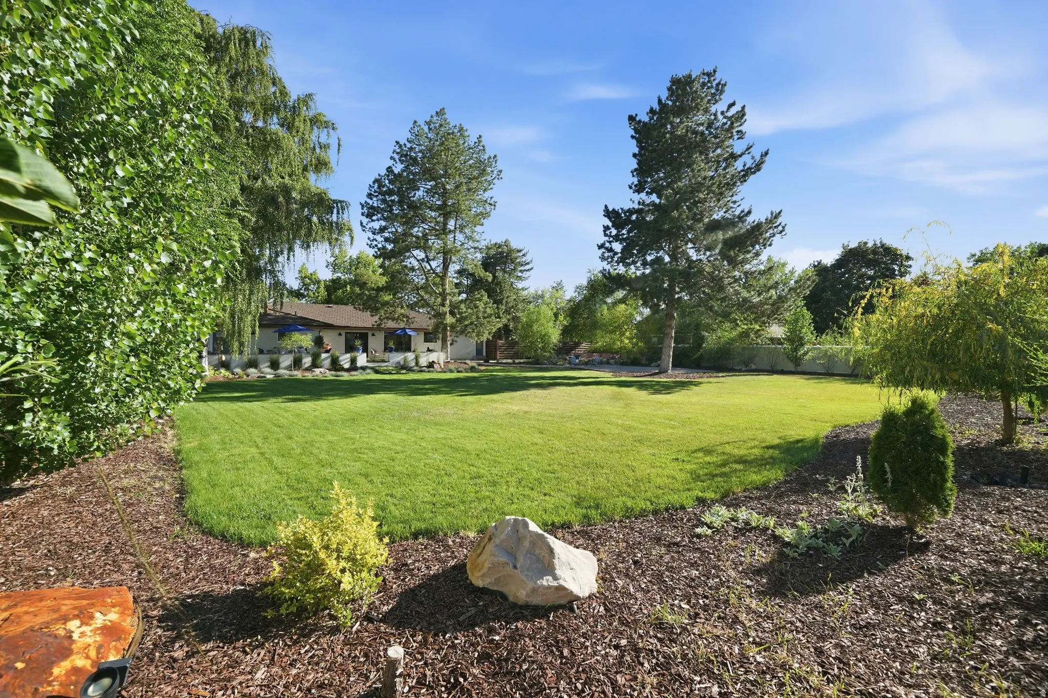 Expansive lawn area surrounded by mature trees and landscaped beds