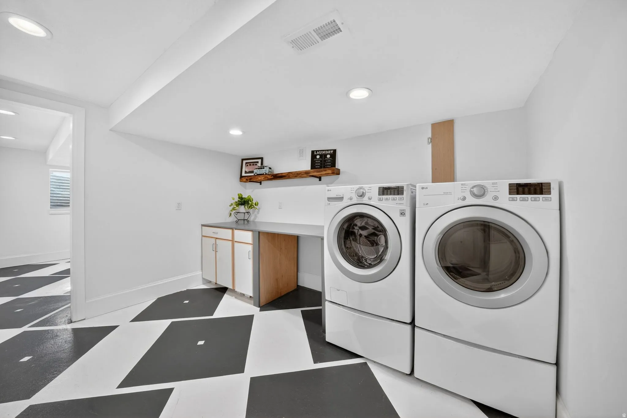 Laundry area featuring a side-by-side washer and dryer, integrated countertop space, recessed lighting, and a floating wood shelf
