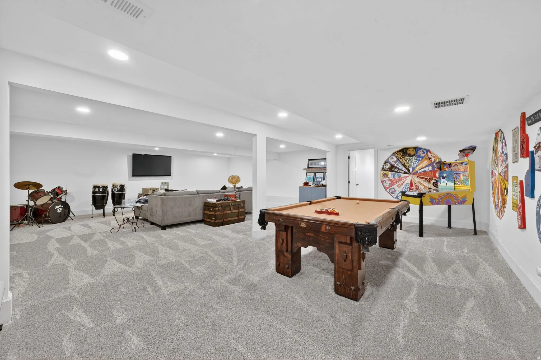 Spacious recreation room featuring light gray patterned carpeting, recessed lighting, and white walls