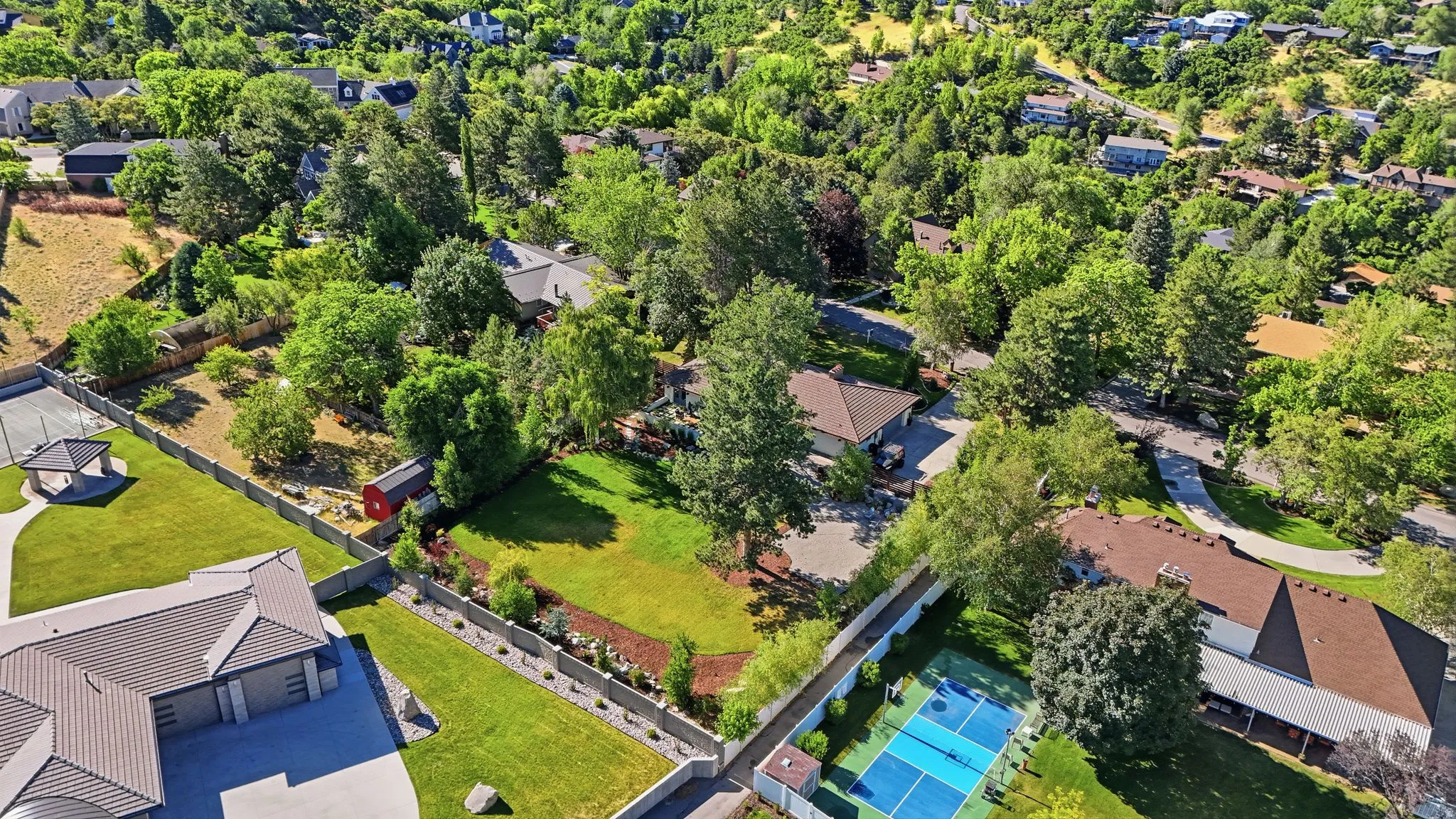 Expansive residential property featuring a full-size tennis court with blue and green surfacing