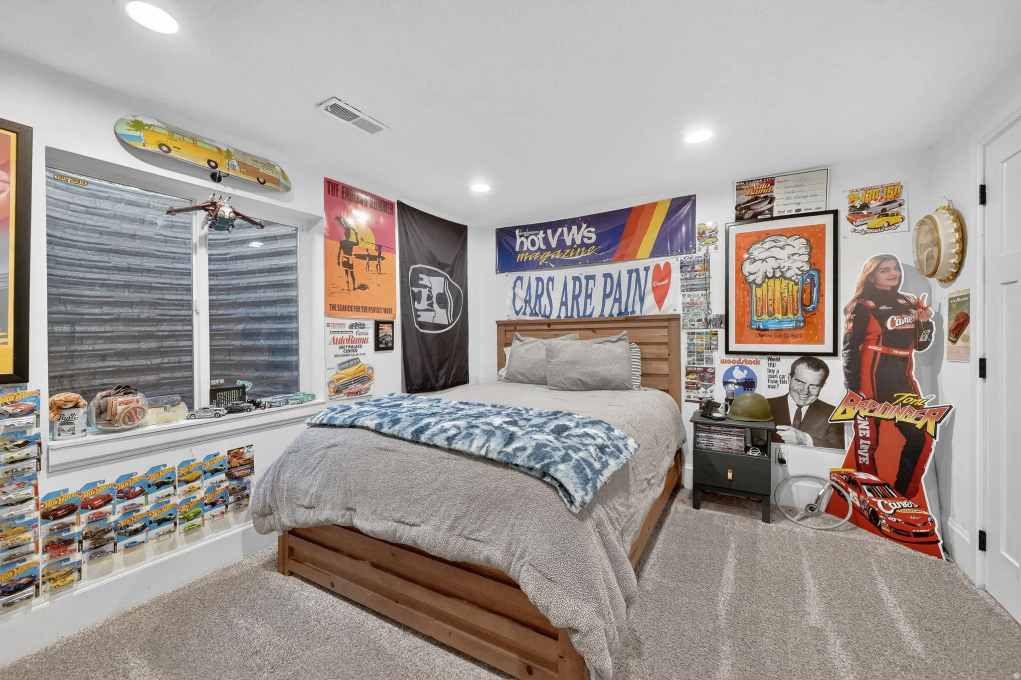 Carpeted bedroom featuring a wood-finish bed frame, recessed lighting, and a white interior door
