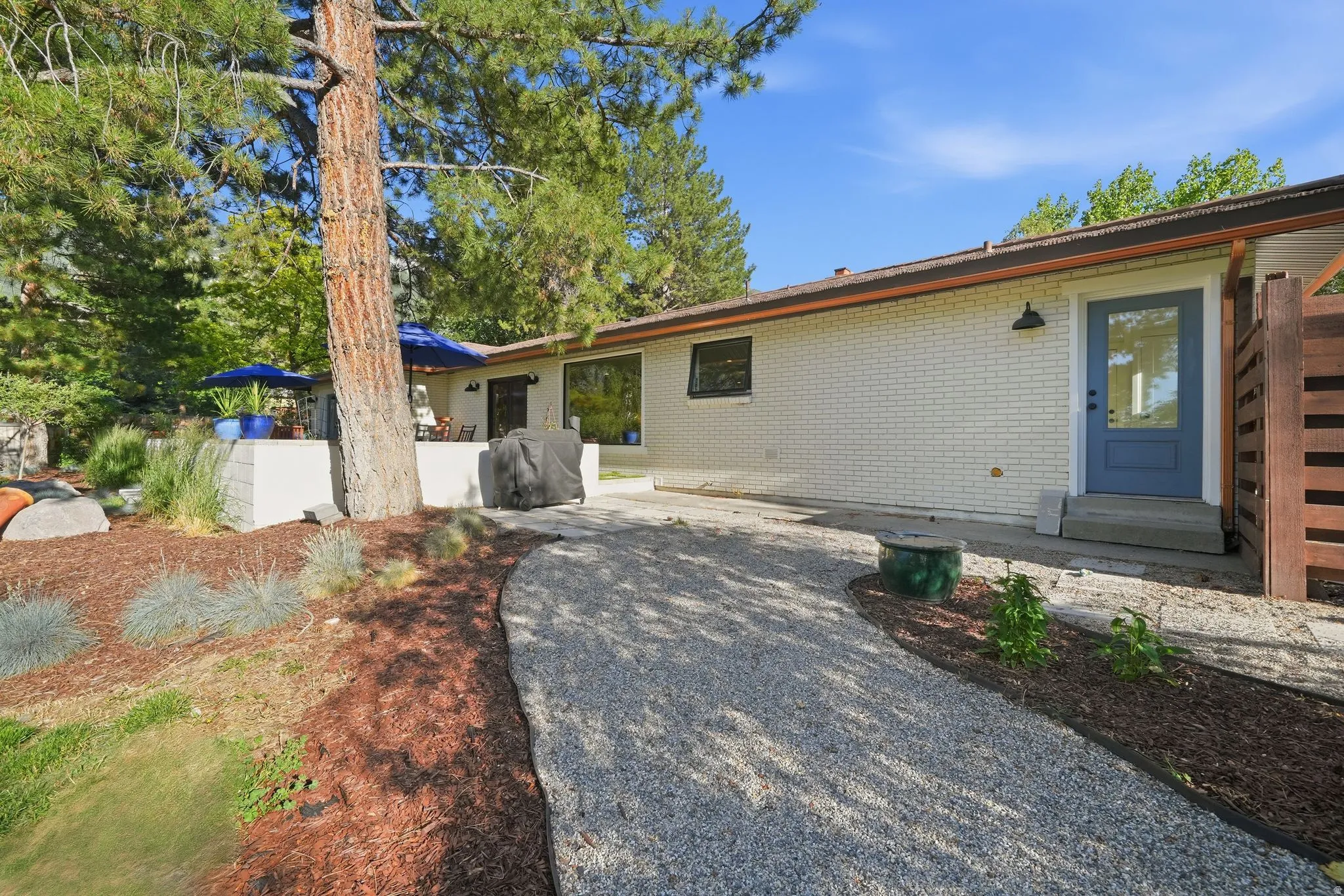 Exterior featuring a light brick facade and a distinct blue entry door with a glass panel