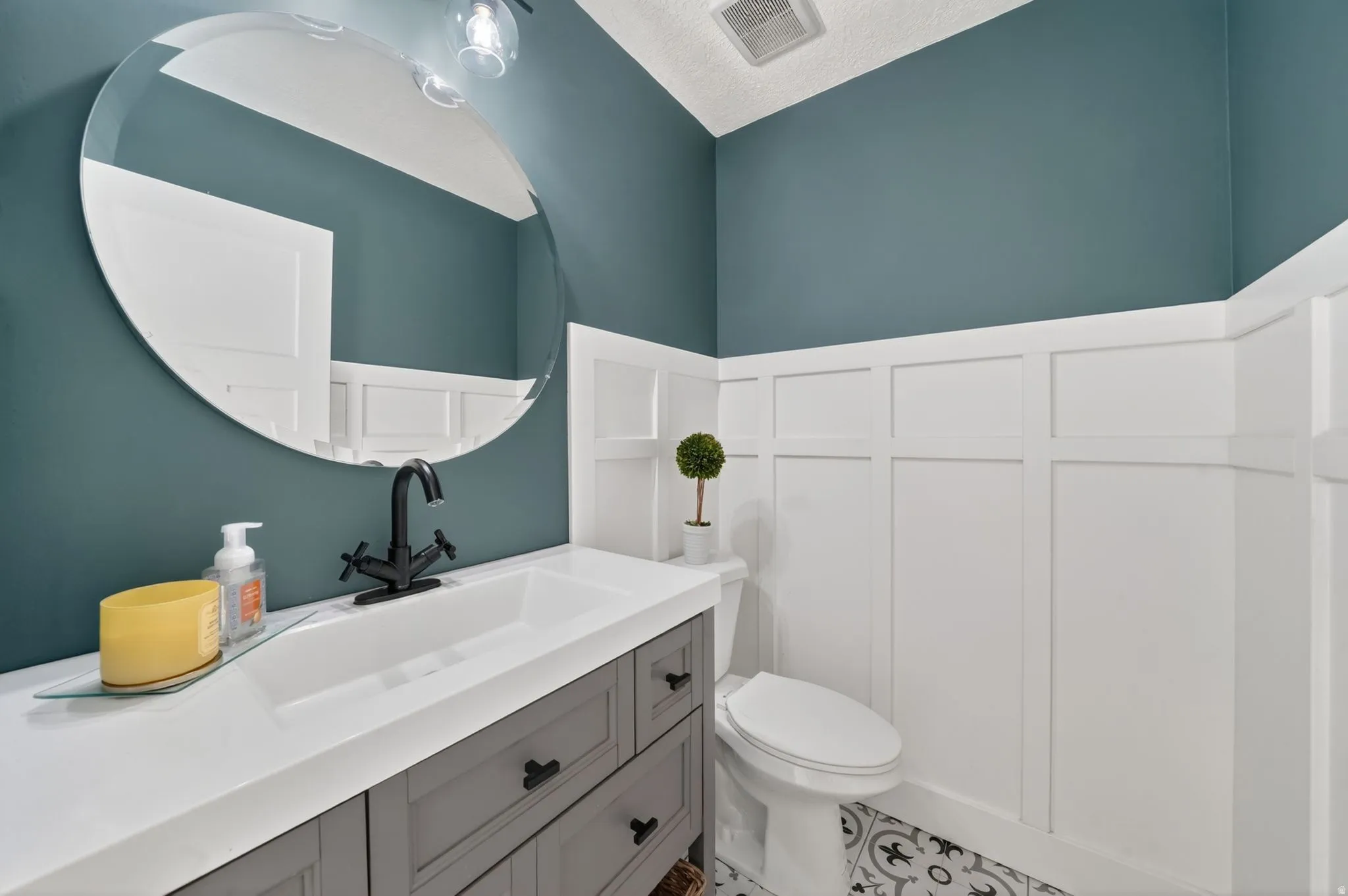 Modern bathroom featuring a single vanity with integrated sink, matte black faucet, and gray cabinetry