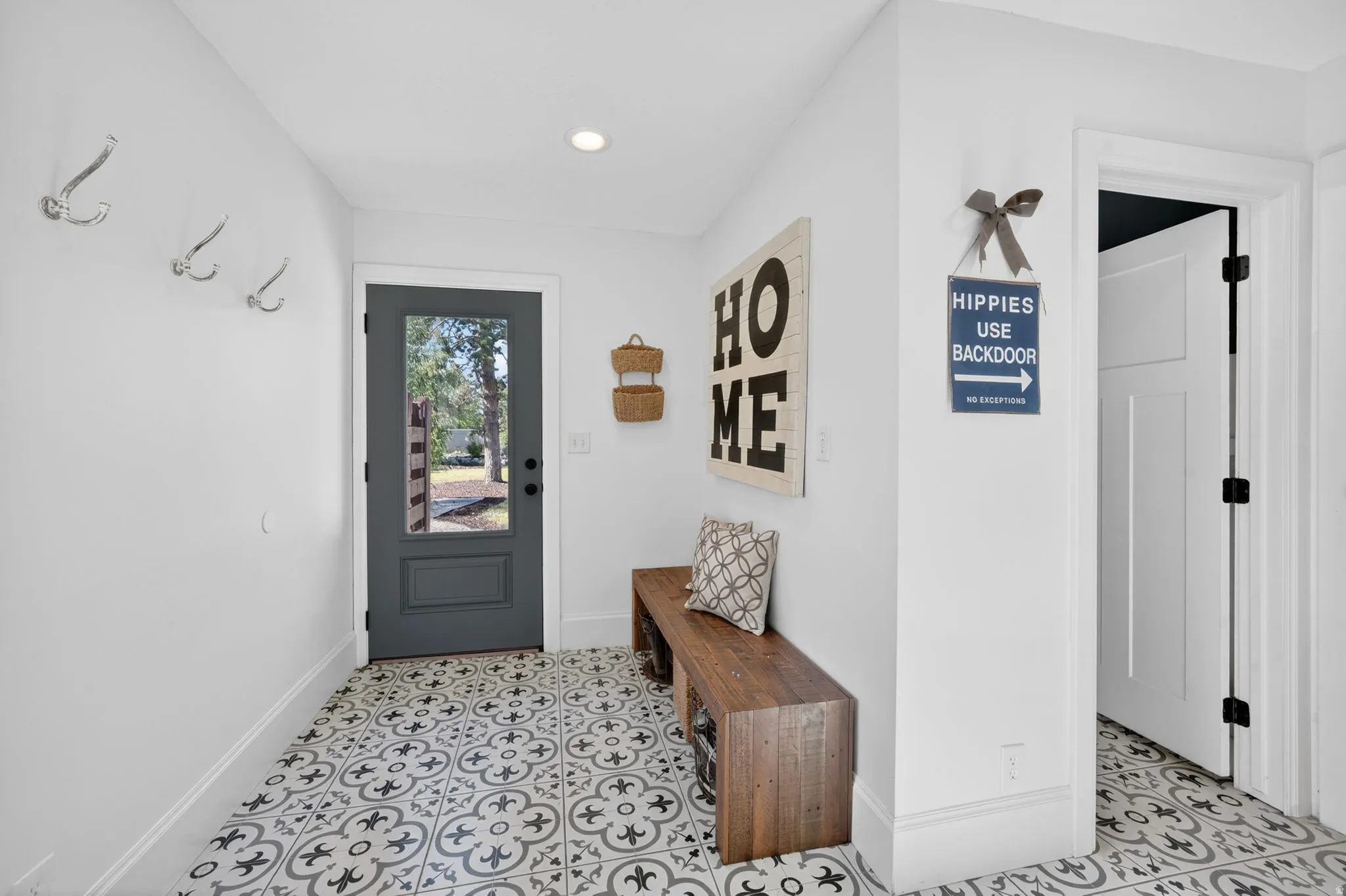 Entryway featuring patterned floor tiles, a dark gray door with an integrated window, and recessed ceiling lighting