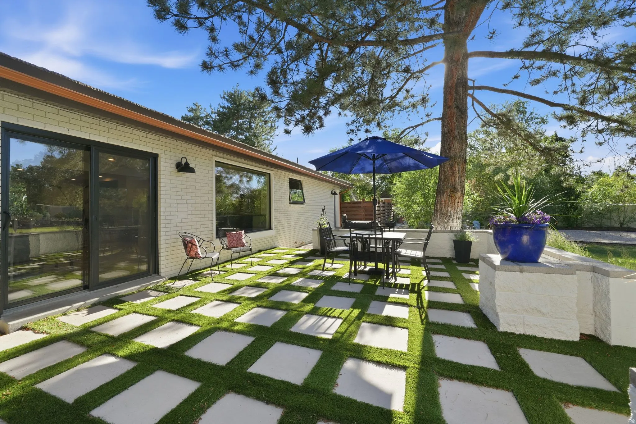 Exterior patio featuring a geometric paver and artificial turf design