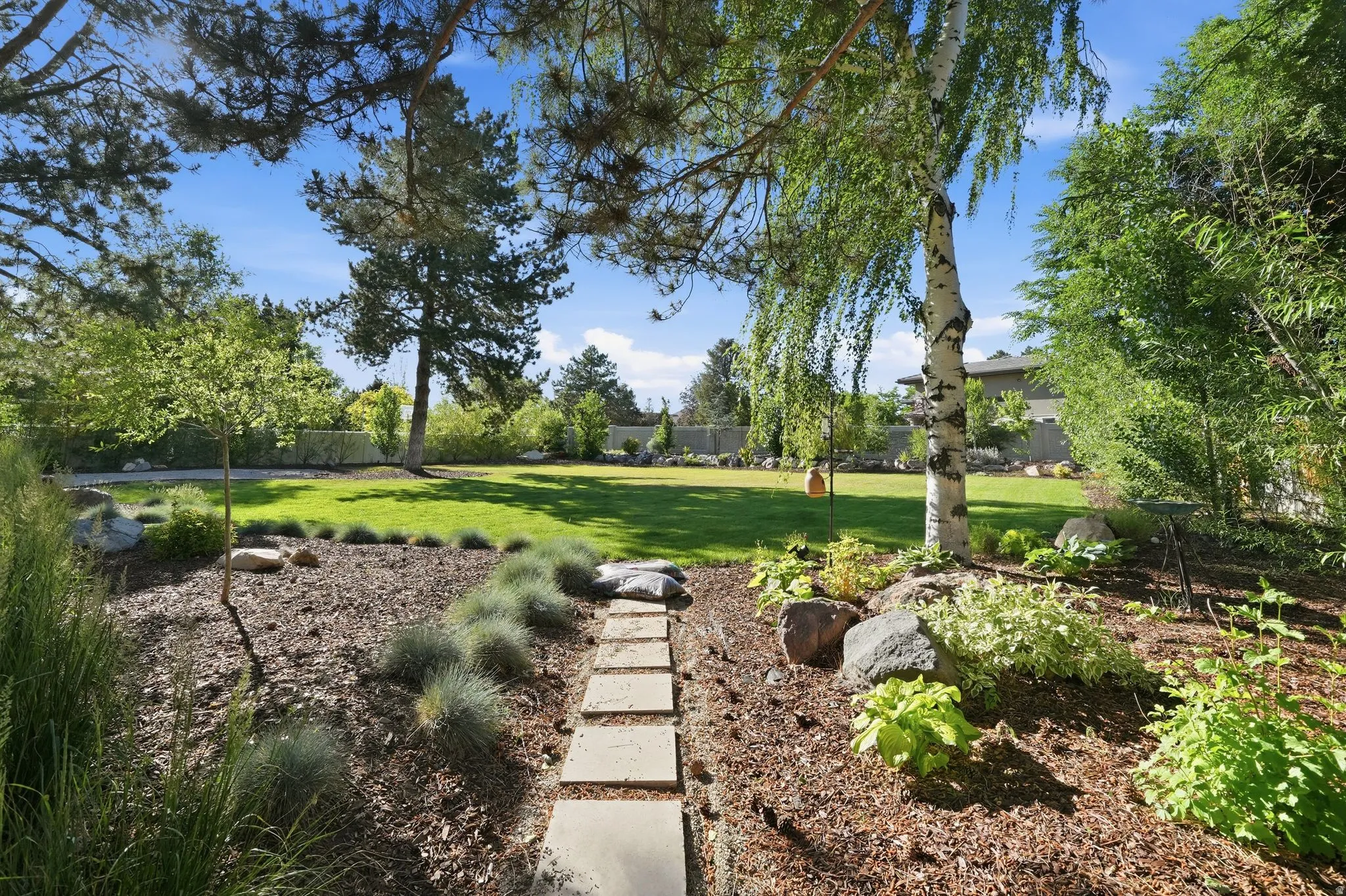 Expansive lawn area bordered by mature trees and varied landscaping
