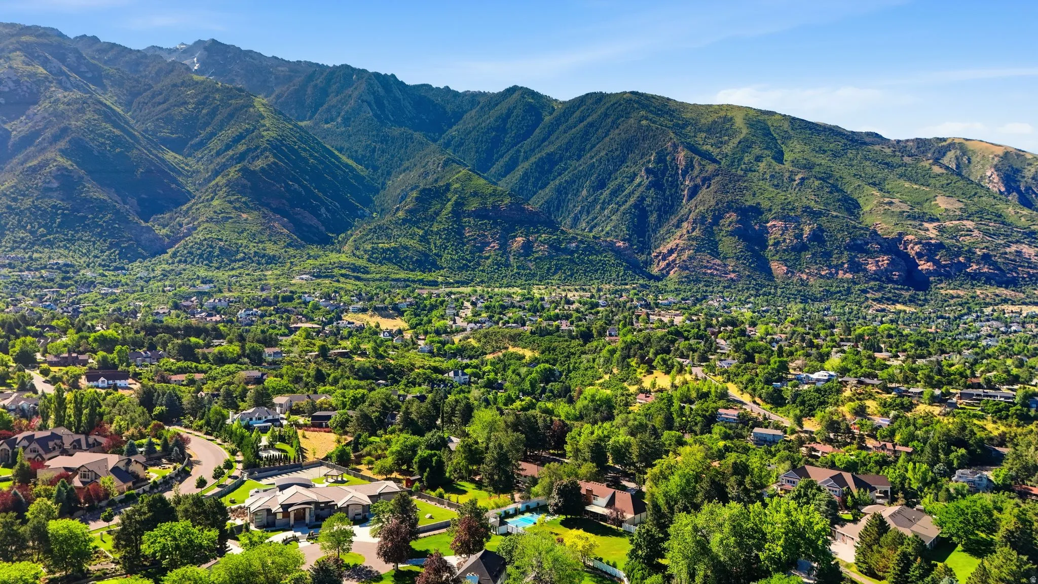 Expansive mountain landscape with a residential area featuring lush green trees and varied architectural styles