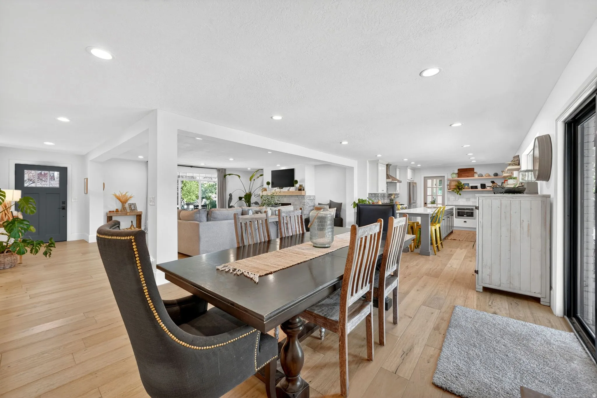 Open concept living space featuring wood-finish flooring, recessed lighting, a modern entry door with decorative glass, and a kitchen with an island