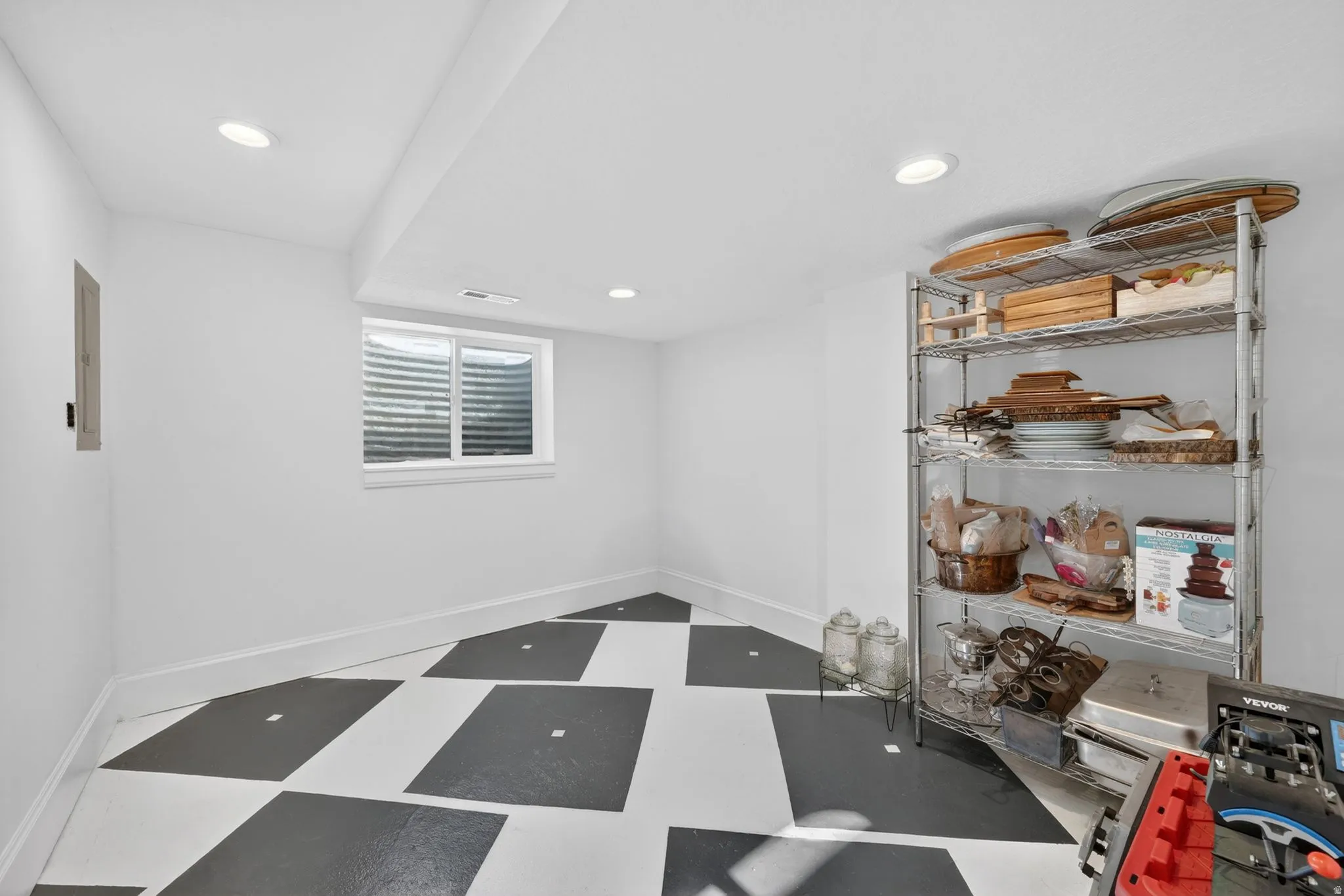 Finished basement space featuring a checkerboard-patterned floor, recessed lighting, and a white-trimmed egress window