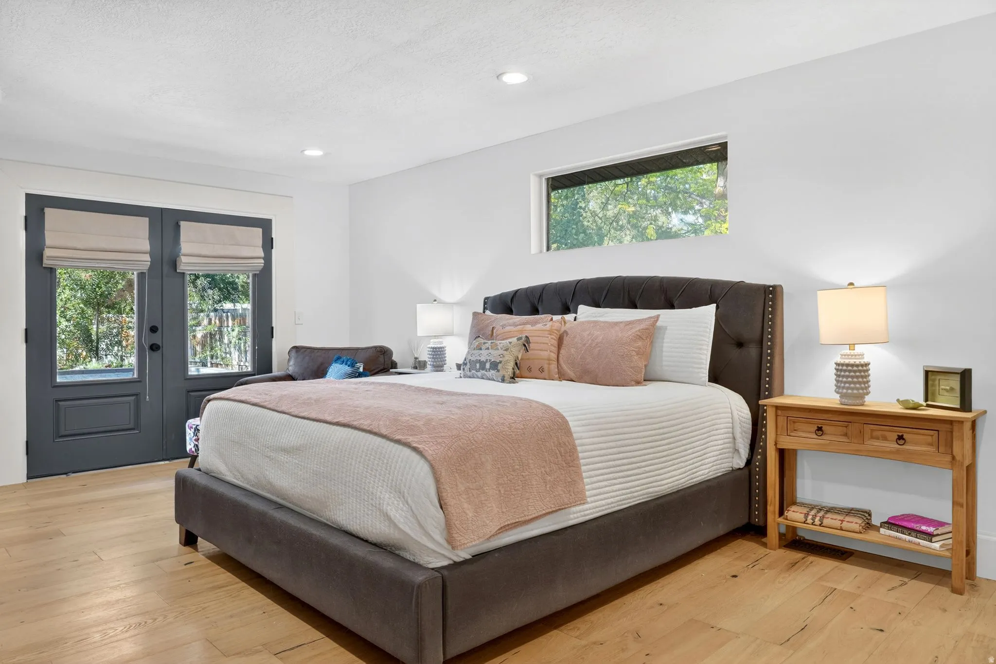 Bright bedroom featuring light wood-finish flooring, white walls, and recessed lighting