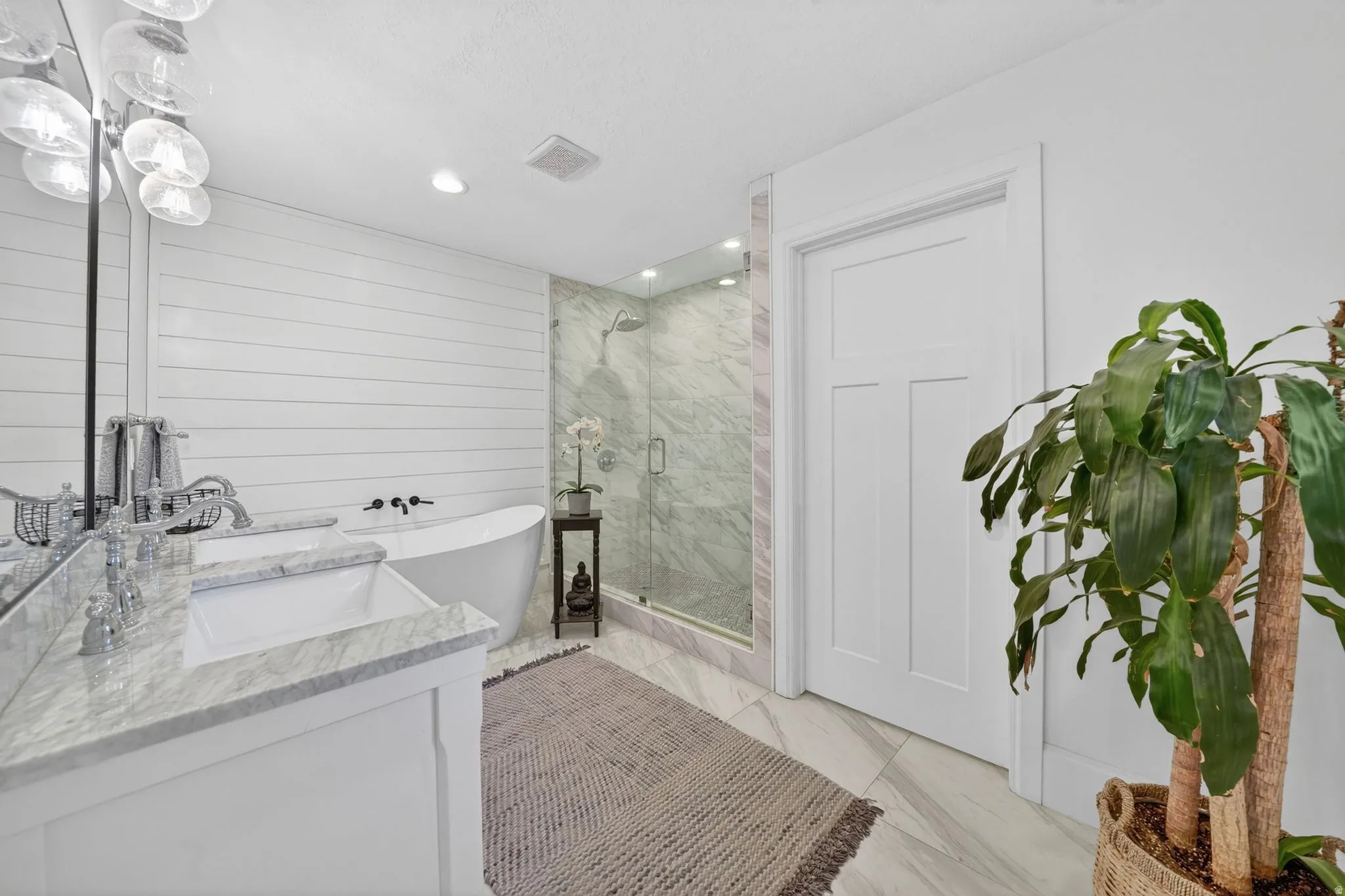 Freestanding soaking tub complemented by a glass-enclosed shower with tiled walls