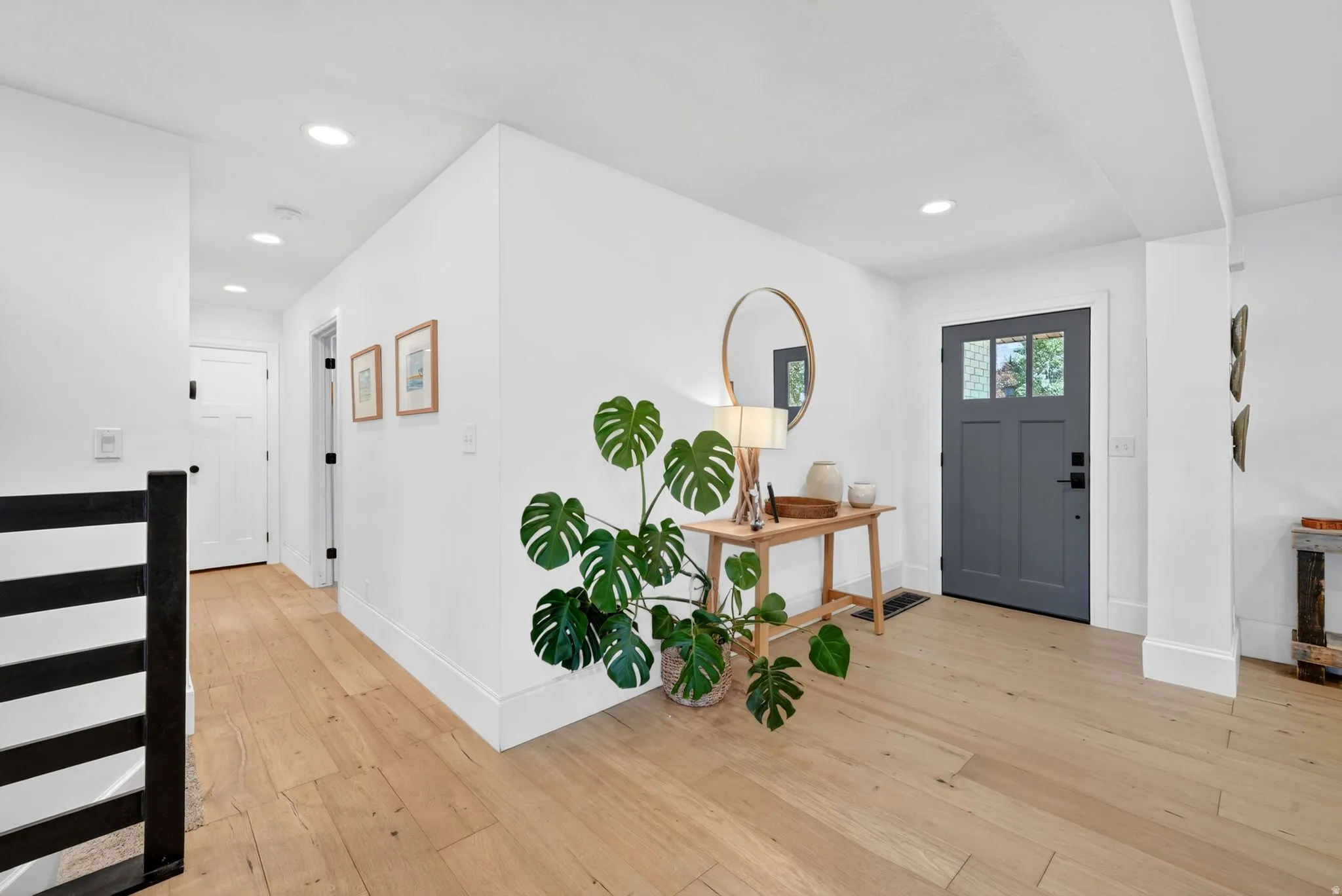 Entryway featuring a charcoal gray door with glass paneling, wood-finish flooring, recessed lighting, and white baseboards