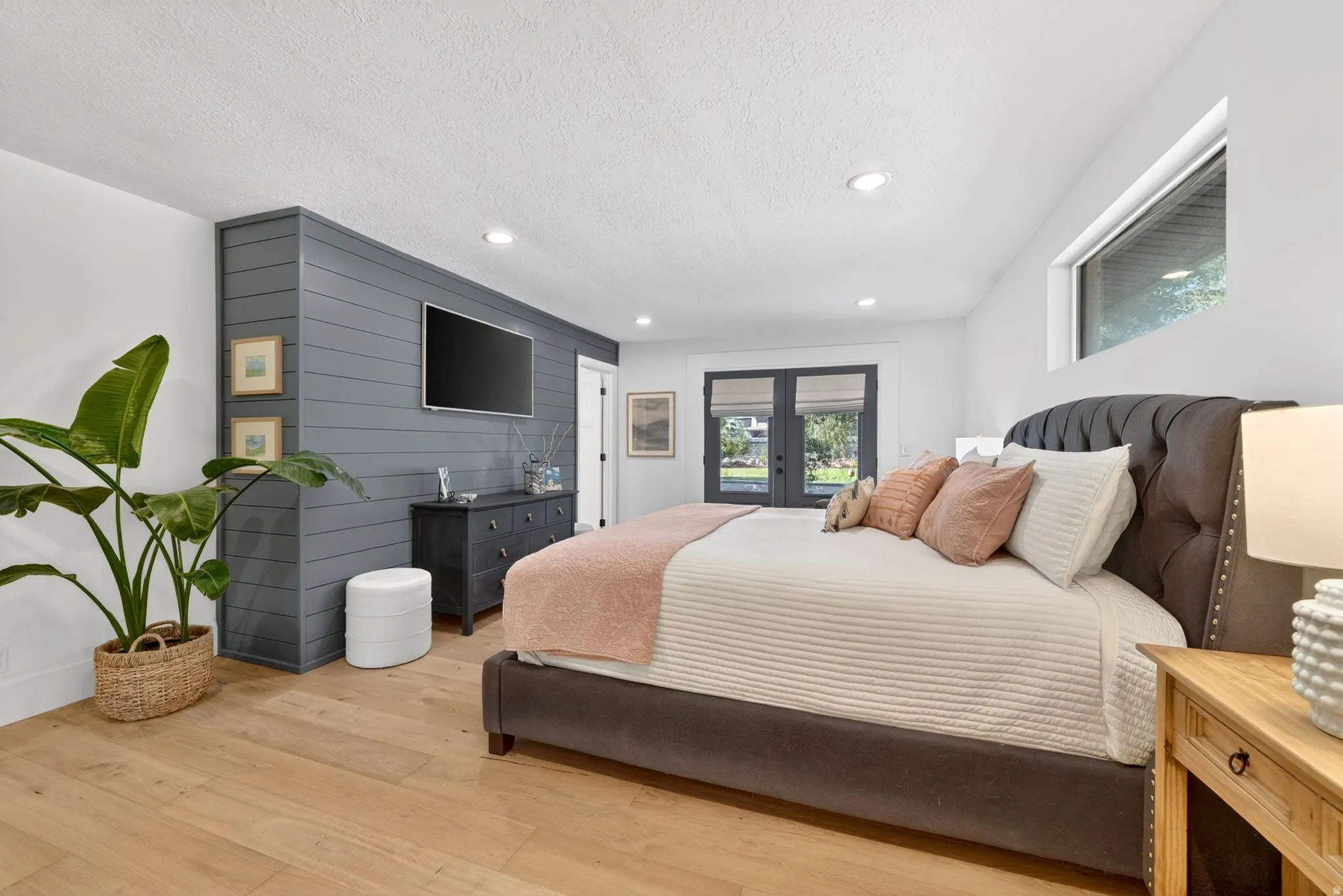 Light wood-finish flooring complements a feature wall with horizontal paneling in a neutral tone