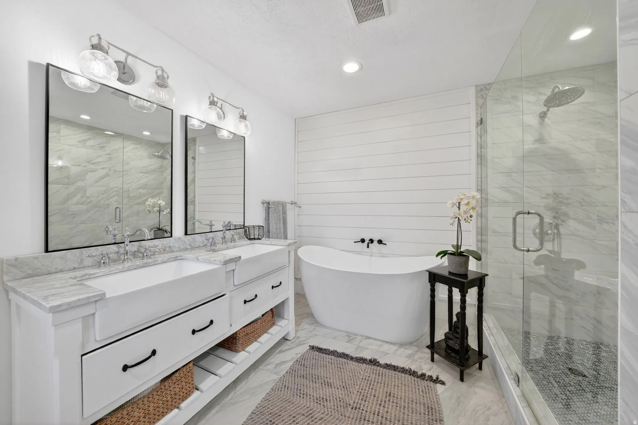 Dual vanity with farmhouse-style sinks, stone countertops, and overhead lighting