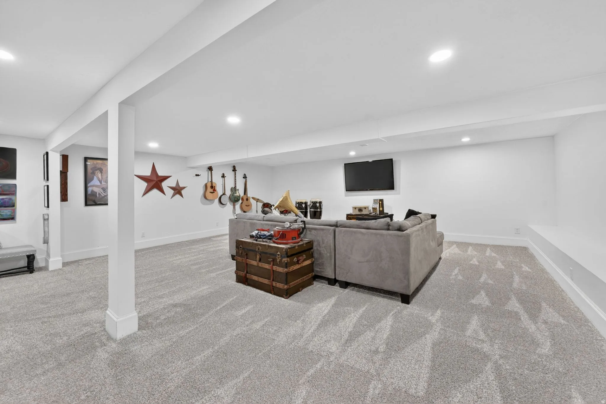 Spacious finished basement featuring recessed lighting, light-toned patterned carpeting, crisp white walls, and a built-in wall bench