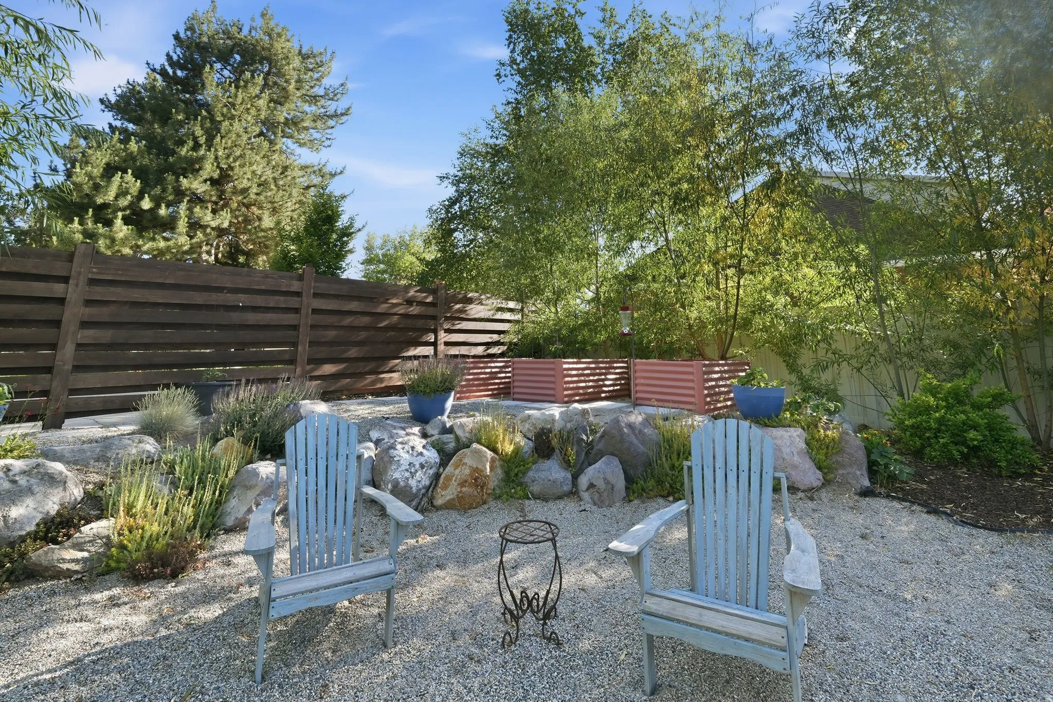 Gravel patio area featuring a slatted wood fence and established landscaping