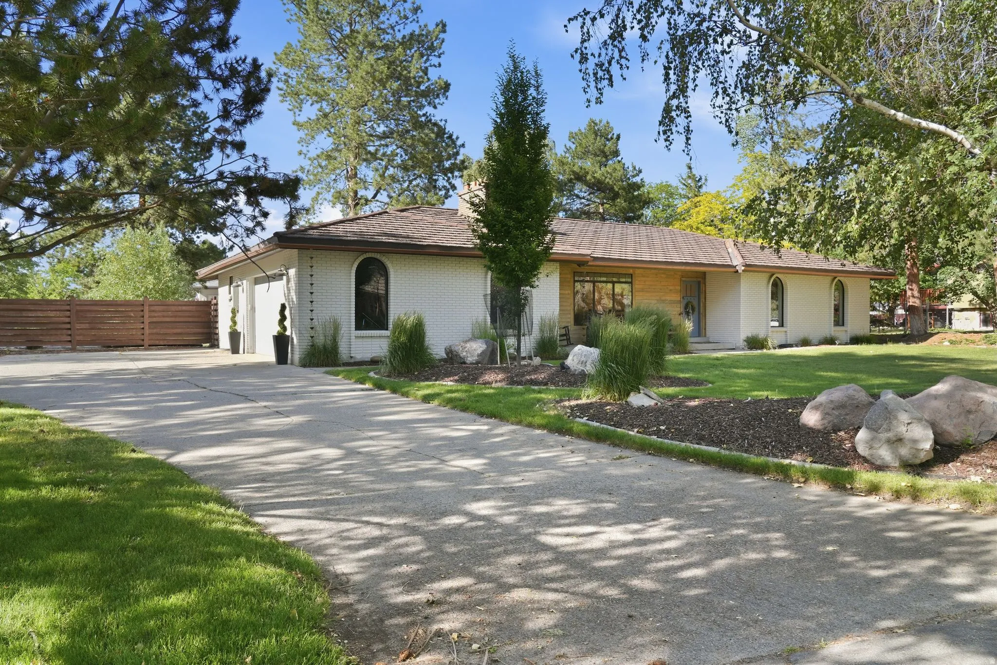 Ranch-style residence featuring a textured exterior, gabled roofline, arched windows, and an attached two-car garage