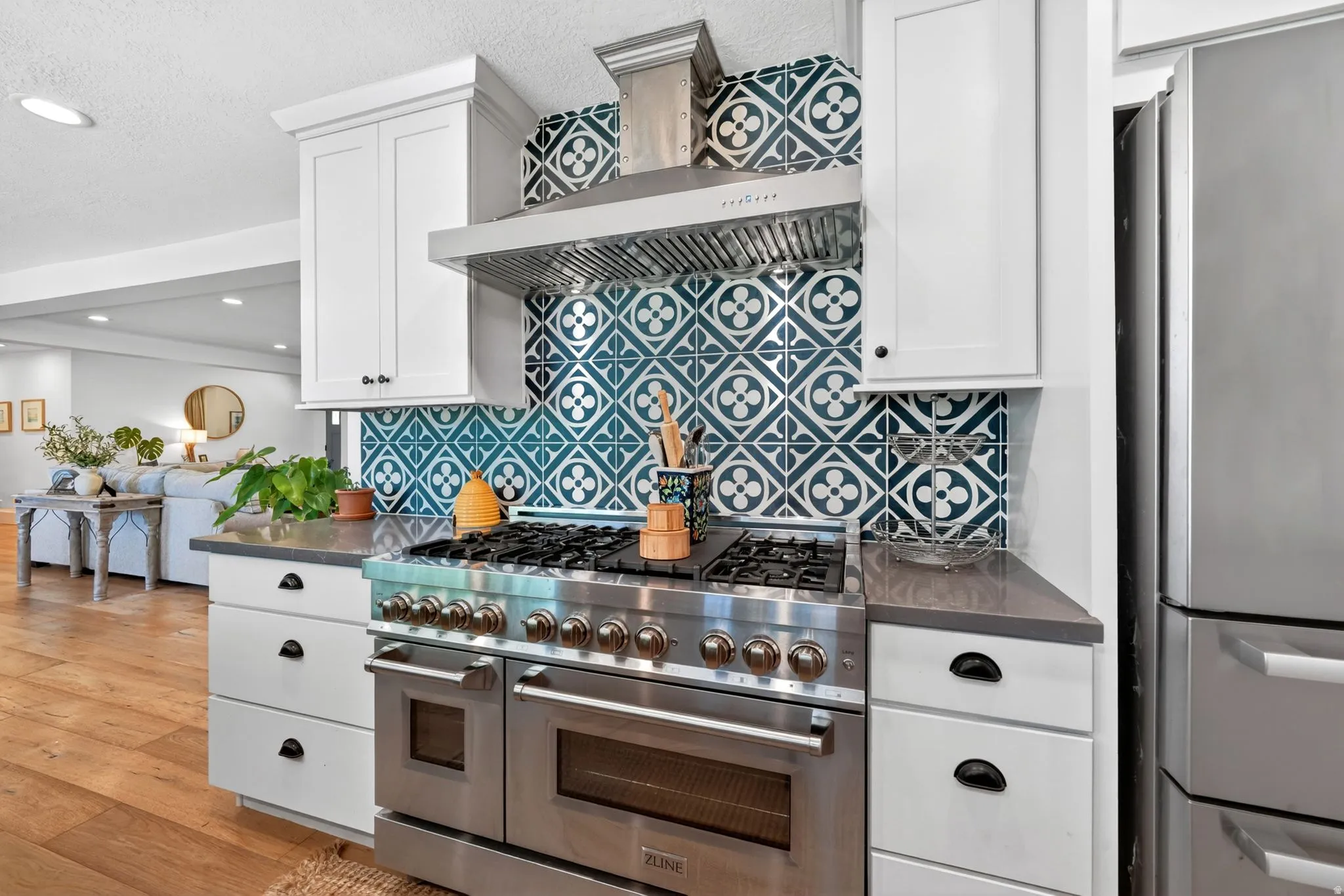 Gourmet kitchen featuring a stainless steel range with multiple burners, integrated ovens, a coordinating stainless steel range hood, and a decorative patterned tile backsplash