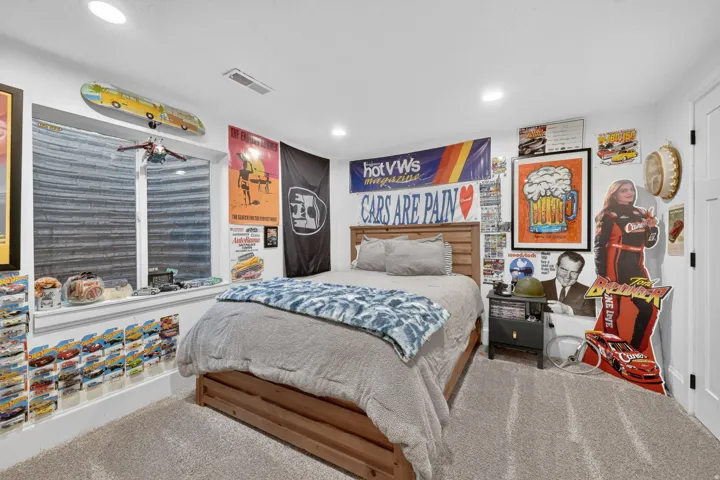 Carpeted bedroom featuring a wood-finish bed frame, recessed lighting, and a white interior door