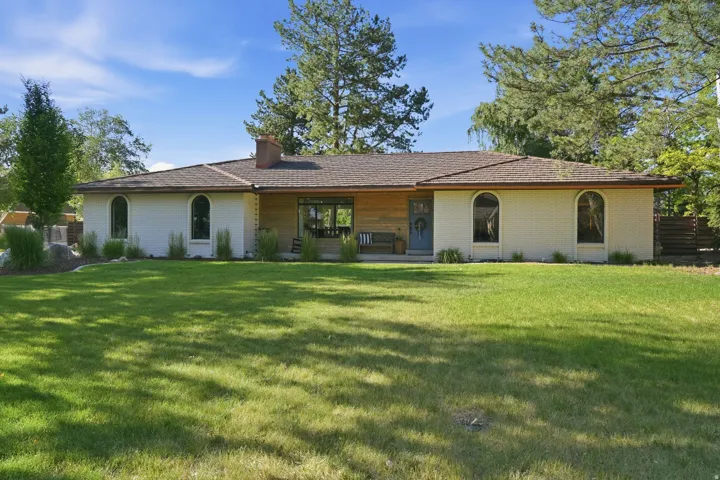 Ranch-style exterior with a brown shingle roof, white brick façade, and arched windows