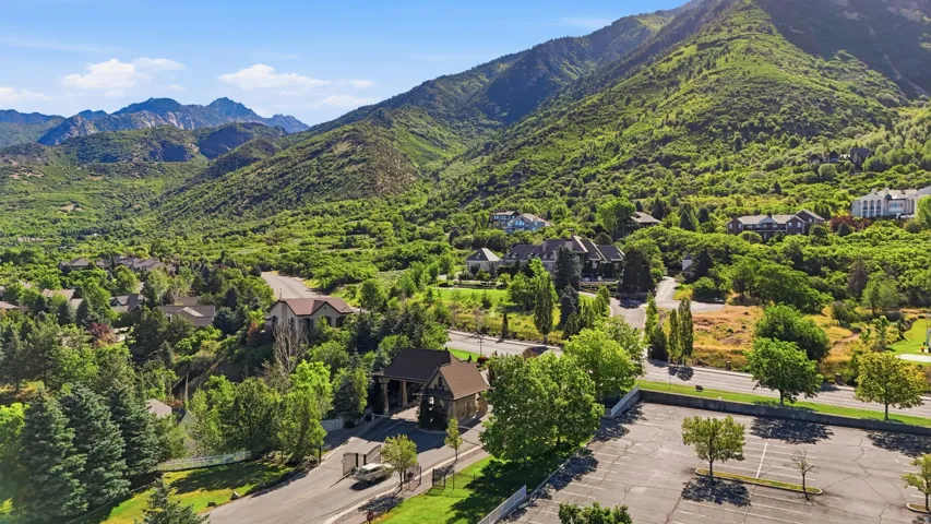Mountain-backed community featuring mature trees, residential properties with varied architectural styles, and paved roads