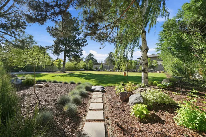 Expansive lawn area bordered by mature trees and varied landscaping