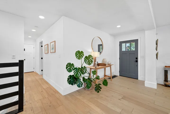 Entryway featuring a charcoal gray door with glass paneling, wood-finish flooring, recessed lighting, and white baseboards