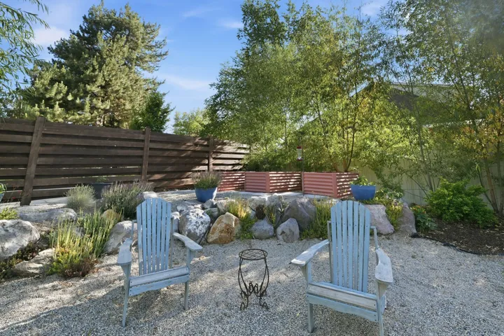 Gravel patio area featuring a slatted wood fence and established landscaping